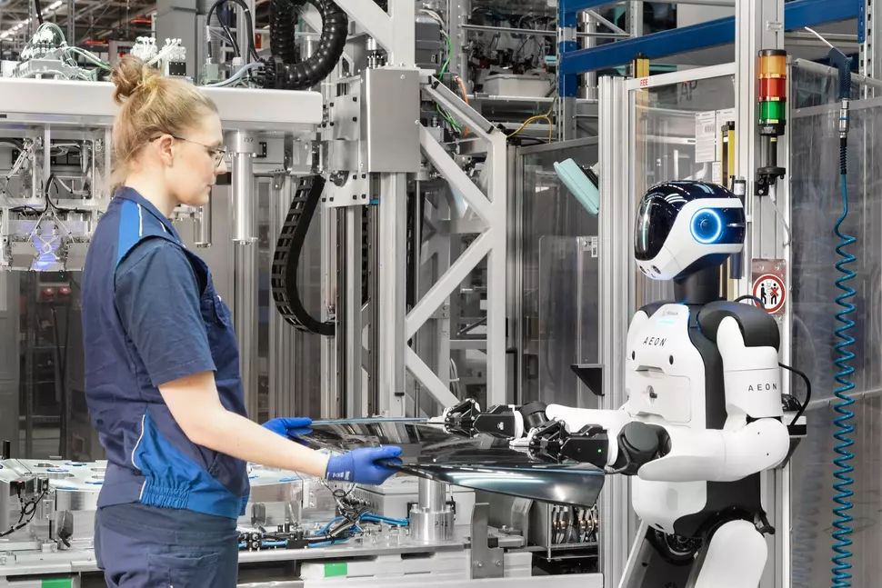 Female employee interacts with the humanoid robot in production at the BMW plant in Leipzig