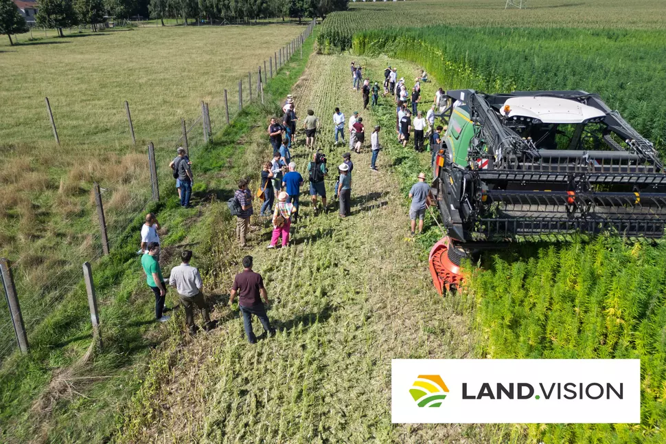 Participants in a technology transfer event in the field observing a hemp harvesting machine