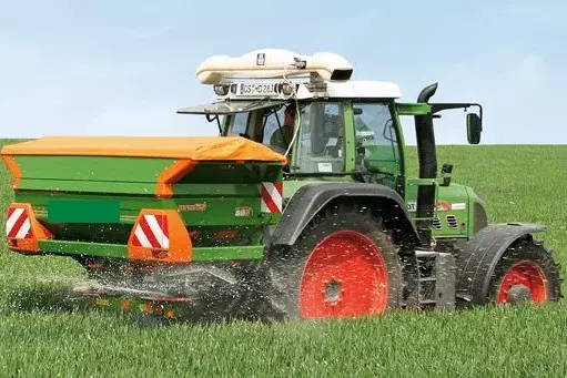 Mit Sensorik der Agricon GmbH ausgestatteter Traktor ermittelt während der Feldüberfahrt die jeweils notwendige Menge an Stickstoffdünger, die vom Streuer auf dem Feld ausgebracht werden muss. (Quelle: Agricon GmbH)